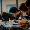 Foto que muestra personas escribiendo en un papel 