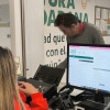 Foto que muestra dos personas hablando y un computador 