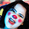 Imagen de una mujer joven que tiene su cara pintada como una payasa.
