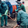 Imagen de tres técnicos de la empresa de Acueducto realizando mantenimiento en un tubo de alcantarillado, de fondo se ve un carro tanque.