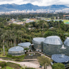 Vista panorámica del Jardín Botánico de Bogotá con Tropicario, zonas verdes y viviendas y edificaciones al fondo