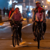 Personas recorren en bicicleta una vía iluminada de Bogotá durante una jornada de Ciclovía nocturna