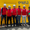 Foto que muestra un grupo de personas con chaleco rojo y casco blanco sonriendo 