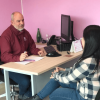 Dos ciudadanas siendo atendidas por un funcionario en una oficina.