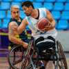 paradeportistas compiten en un partido de baloncesto en silla de ruedas dentro de un coliseo de Bogotá.