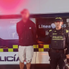 Hombre capturado junto a un policía y una patrulla.