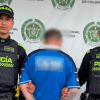 Hombre capturado, de espaldas, en medio de dos policías.