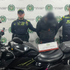 Foto de uniformados de la Policía con el hombre capturado y la motocicleta incautada.