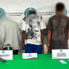 Tres hombres capturados, en medio de dos policías.