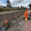 Foto que muestra personas con el uniforme de Aguas Bogotá limpiando un canal de agua