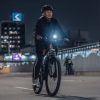 Mujer transita en bicicleta en calle de Bogotá durante Ciclovía Nocturna.