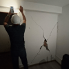 Foto que muestra una persona con un casco revisando una pared con una grieta 