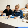 Foto que muestra personas sentadas escribiendo en un escritorio 