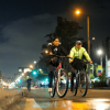 Tres personas recorren una vía durante la Ciclovía Nocturna en Bogotá.