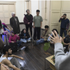 Imagen de varios jóvenes en una aula escuchando a un hombre mayor que habla.