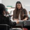 Foto que muesta dos mujeren hablando, computadores y una impresora