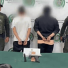 Dos hombres capturados, en medio de dos policías.