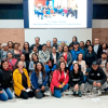 Grupo de personas participante en el Cuarto Diálogo Ciudadano del IDIGER en Ciudad Bolívar posan en un auditorio con una pantalla para proyectar presentaciones de fondo.