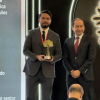 Foto que muestra dos personas sonriendo con un premio en la mano