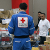 Personal de la Cruz Roja Colombiana organiza y clasifica donaciones en un centro de acopio con cajas, mercados, elementos de ayuda humanitaria y carritos de transporte en Bogotá.