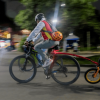 Persona adulta y menor de edad recorren una vía en bicicleta durante una jornada nocturna en Bogotá.