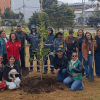 Grupo de personas posa alrededor de un árbol recién sembrado durante una jornada de siembra y restauración ecológica en Bogotá.