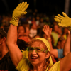 Persona con guantes y gafas de color verde levanta los brazos entre el público durante un evento nocturno al aire libre en Bogotá.