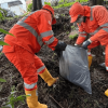 Foto que muestra dos personas con el uniforme de Aguas Bogotá levantando residuos de la calle