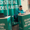 Foto que muestra un señor con un computador y avisos con el texto Secretaría Distrital del Hábitat