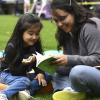 Imagen de una señora con una niña sobre el pasto leyendo un libro de BibloRed