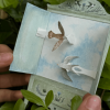 Imagen de una figura de una ave café claro y de otra ave blanca hechas en papel.