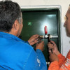 Dos funcionarios del Acueducto revisando el medidor del agua