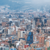 Vista panorámica de Bogotá con edificios residenciales, vías principales, zonas comerciales y amplias áreas urbanas bajo un cielo nublado.