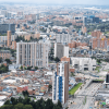Vista panorámica de Bogotá con edificios residenciales, vías principales, zonas comerciales y amplias áreas urbanas bajo un cielo nublado.
