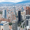 Vista panorámica de Bogotá con edificios residenciales y empresariales de gran altura, corredores viales, centro financiero y cerros orientales visibles al fondo bajo un cielo nublado.