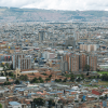 Vista panorámica de Bogotá con edificios, zonas industriales y cerros bajo cielo nublado.