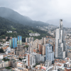 Vista panorámica de Bogotá con edificios residenciales y comerciales de diferentes alturas en primer plano, y los Cerros Orientales en un día nublado.