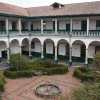 Foto que muestra un edificio de dos pisos con paredes blancas y verdes y un jardín en la mitad 