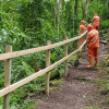 Foto que muestra tres personas instalando barandas en madera en un sendero ecológico 