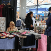 Foto que muestra un grupo de personas en una feria donde se exhiben artesanías y prendas de vestir. 
