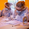Foto que muestra dos personas con gorro y guantes de enfermería escribiendo en un papel