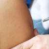 Foto que muestran unas manos colocando una vacuna en un brazo 