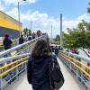 Foto de hombres y mujeres caminando por un puente peatonal en Bogotá.