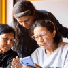 Tres mujeres viendo un celular durante un encuentro en Bogotá.