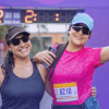 Dos participantes de la Carrera de la Mujer posan frente al arco de meta con números de competencia visibles