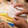 Imagen de manos con tatuajes con libro en hojas pequeño en una biblioteca de Bogotá.
