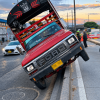 Camión rojo inclinado sobre el separador de una vía de Bogotá, con dos ruedas elevadas. A un costado hay motocicletas de tránsito, personal en la calzada y vehículos circulando en varios carriles.