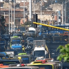 Panorámica de una vía con alta congestión vehicular en Bogotá. Se observan buses de TransMilenio, automóviles, motocicletas y vehículos de carga circulando en varios carriles, junto con agentes de tránsito en la calzada.