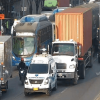 Vehículos particulares, camiones de carga y un bus circulan lentamente en una vía congestionada de Bogotá, con varios carriles ocupados por tráfico denso.