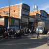 Intersección vial en Bogotá con alto flujo de motocicletas, camiones, vehículos particulares y un ciclista cruzando la vía.